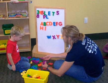 A parent playing with their child near a whiteboard. Sharing a teaching moment.